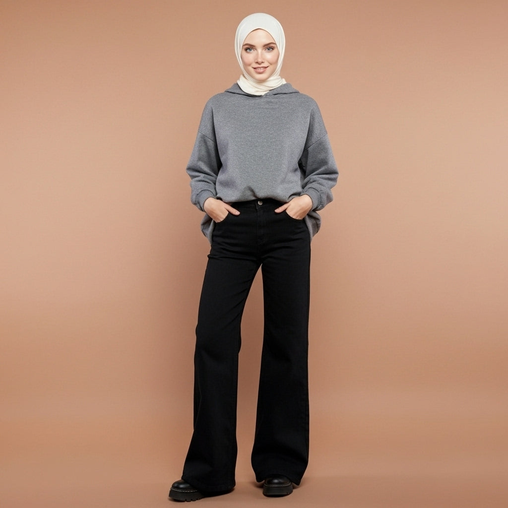 Low waist baggy jeans in black worn by a standing model in side profile, showing a low-rise waistline, straight loose leg cut, clean side seam, full-length silhouette, structured denim drape, and hem falling over the shoe sole