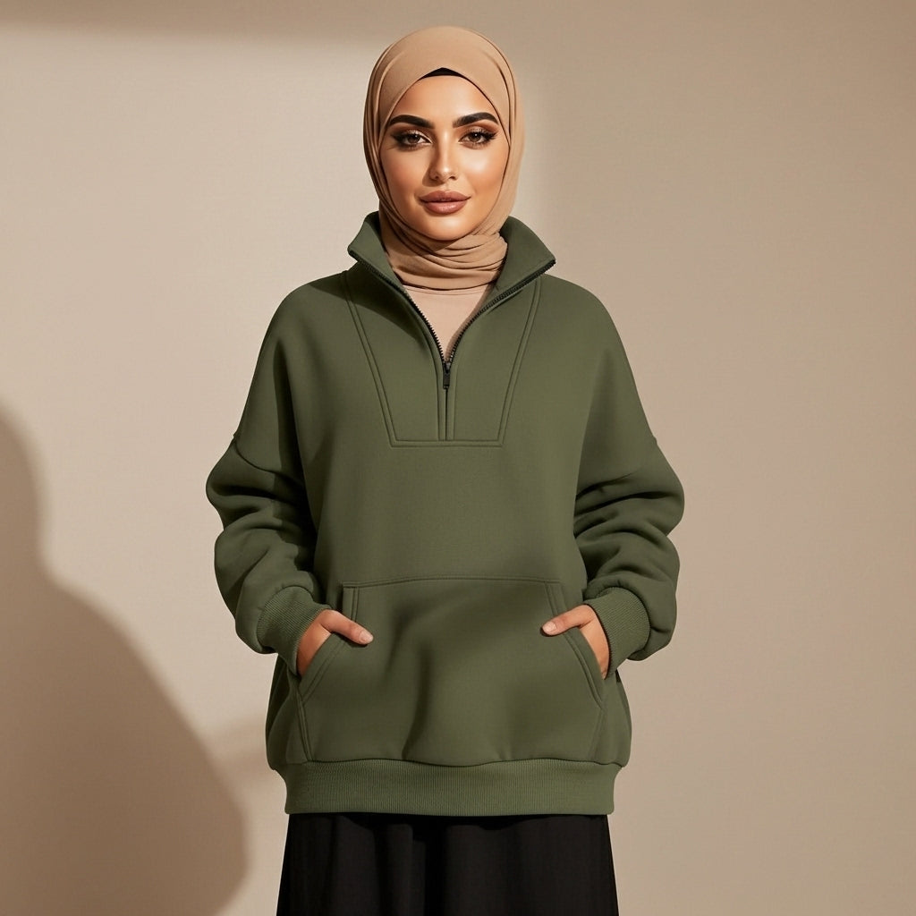 Quarter zip sweatshirt in army green worn by a standing model, showing a relaxed oversized silhouette, quarter zip collar, long sleeves, ribbed hem, and front kangaroo pocket