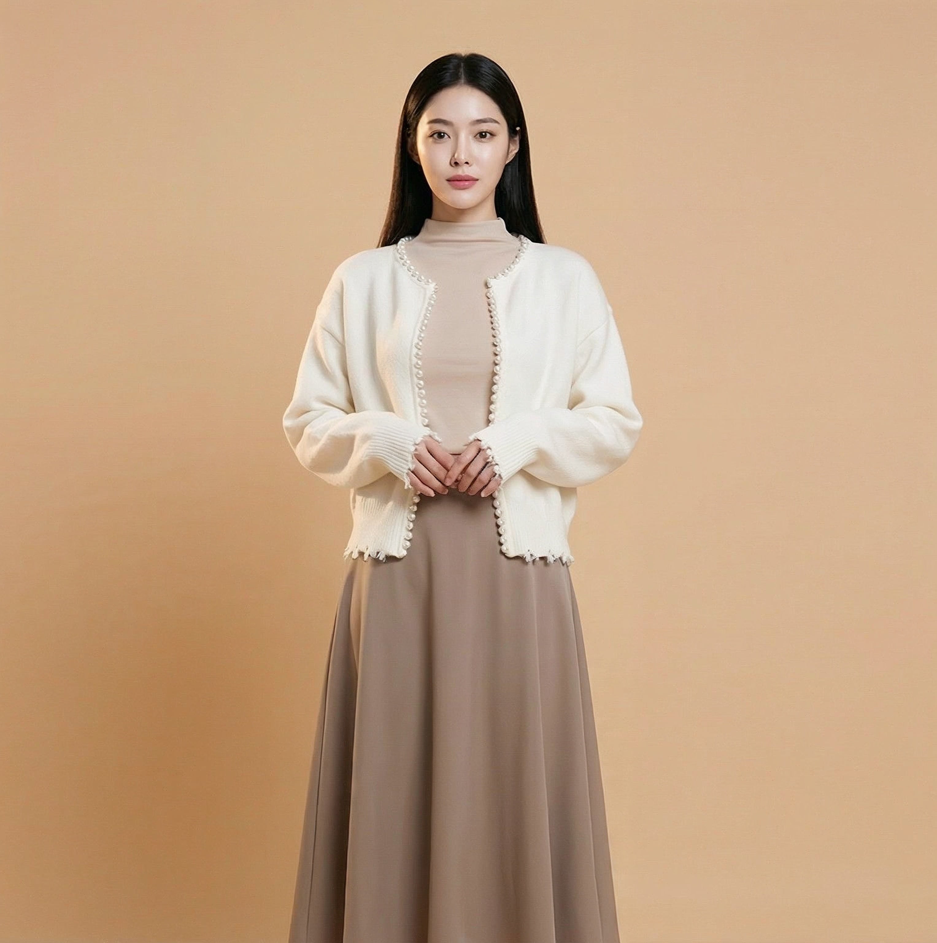 Cropped v neck cardigan in white worn by a standing model, showing a cropped silhouette, long sleeves, pearl button edging, and open-front styling