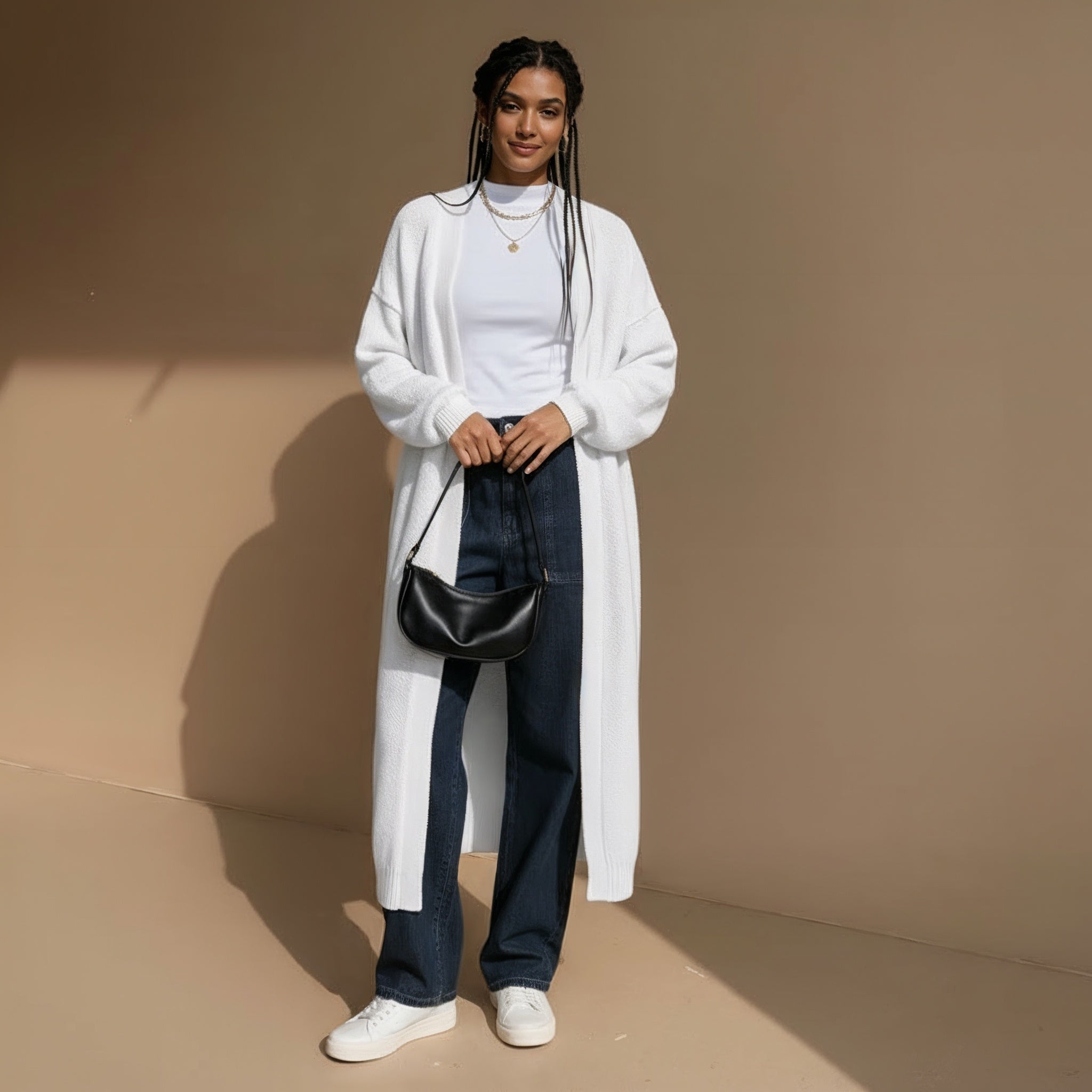 Longline knit cardigan in white worn by a standing model, showing a full-length open silhouette, oversized shape, long sleeves, and straight hemline