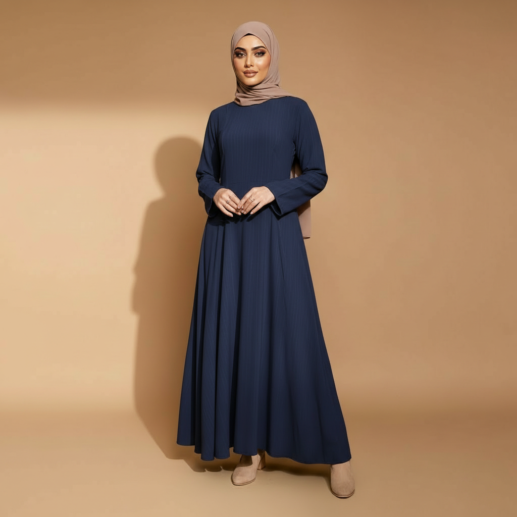 Long sleeve winter maxi dress in navy blue worn by a standing hijabi model facing front, showing a round neckline, full-length sleeves, lightly textured fabric, flowing A-line cut, floor-length hem, and soft vertical movement through the skirt